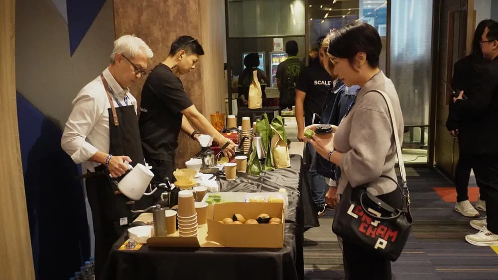 A barista pouring filter coffee for attendees at the SCALECON Jakarta 2025 coffee corner