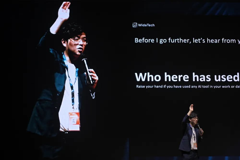 A speaker with a hand raised asking the room who has used an AI tool at SCALECON Surabaya 2026