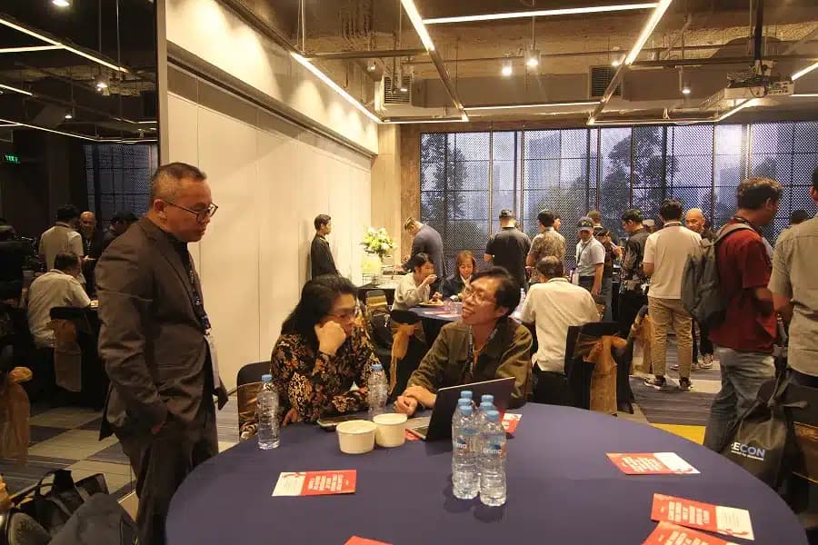 Attendees talking around a table with the room busy behind them at a previous SCALECON
